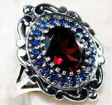 “Secrets of His Promises” Stunning four carat genuine Mozambique fire Garnet surrounded by lab blue sapphires set in solid ornate sterling silver.